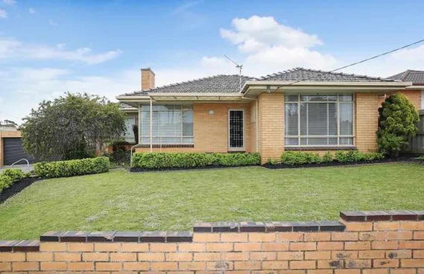 Cream brick home with a tiled roof, established hedging and a low brick front wall in Warrnambool, Victoria