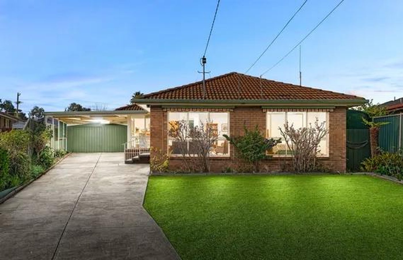 Single storey brick home with a long driveway, carport and lawn in Werribee, Victoria