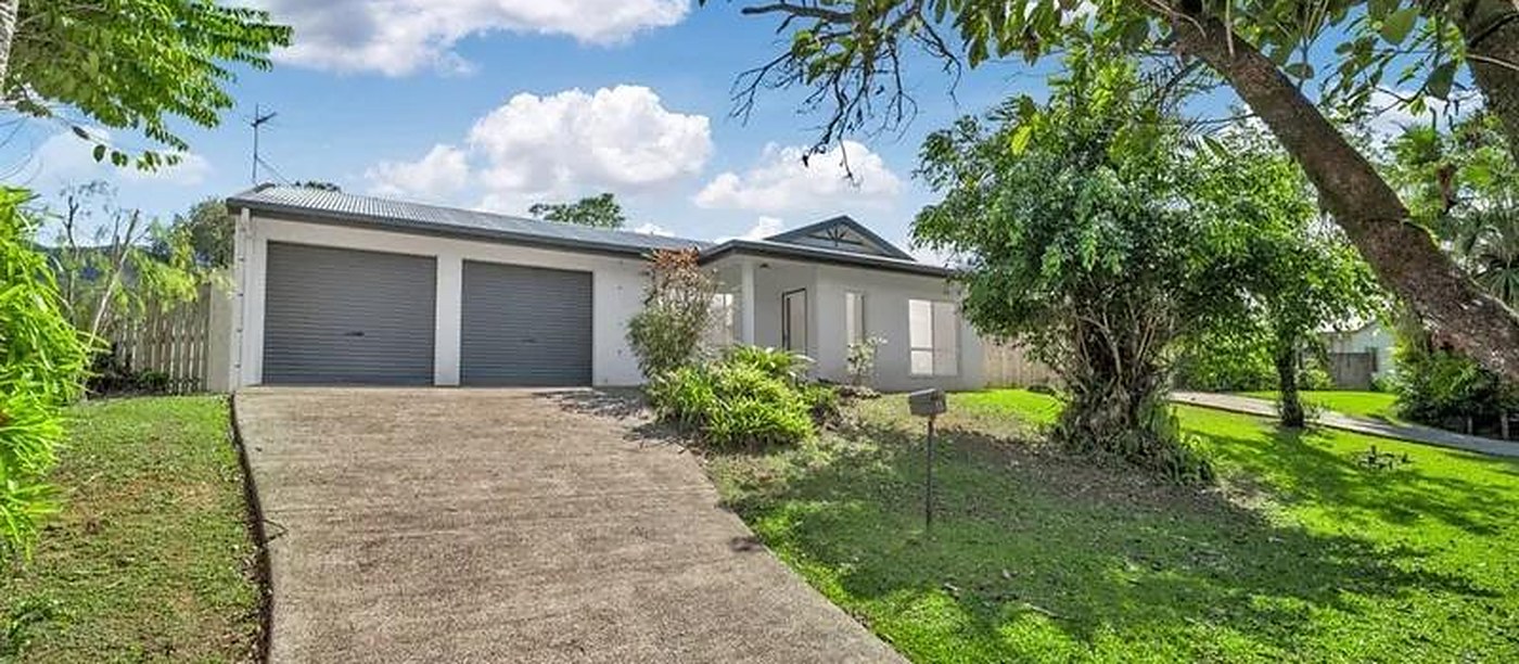 Home with a double garage and a long concrete driveway on a leafy block in Bentley Park, Queensland