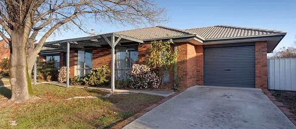 Red brick home with a tiled roof, garage and a covered front verandah in Wodonga, Victoria